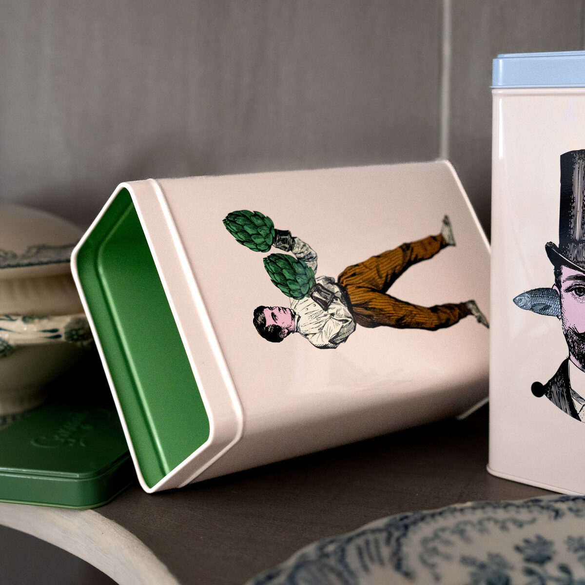 Boîte en métal Gangzaï avec couvercle vert, ornée d’une illustration surréaliste d’un homme avec un artichaut.