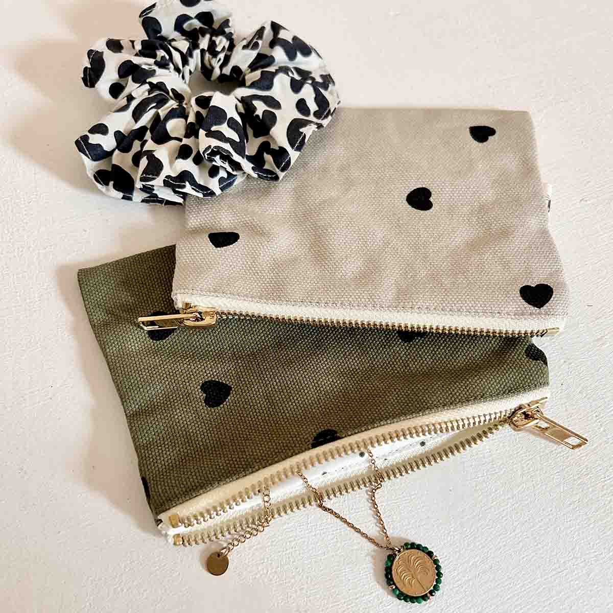 Mini pochette Marie Rose in April couleur sable avec imprimé petits cœurs noirs et bijoux.