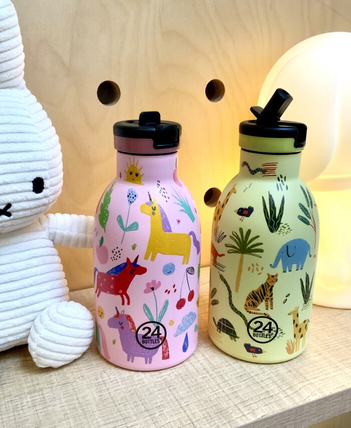 Deux gourdes 24Bottles Kids 300ml à motifs licornes et animaux de la jungle posées sur une étagère avec une peluche Miffy.