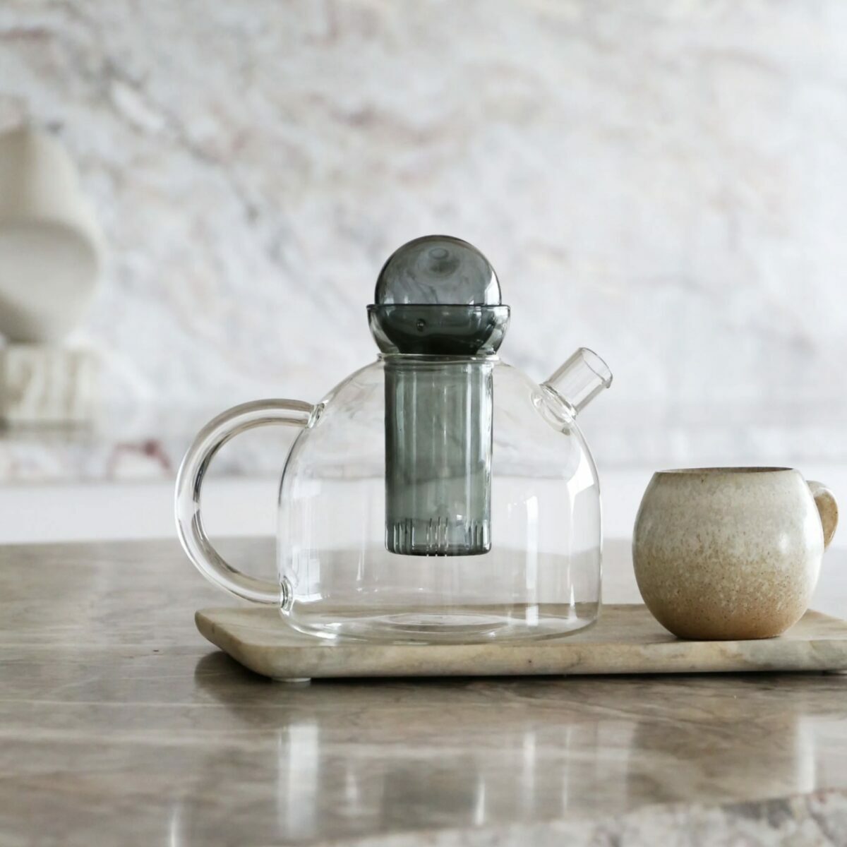 Théière en verre Still Ferm Living avec infuseur en verre teinté gris et couvercle plat.