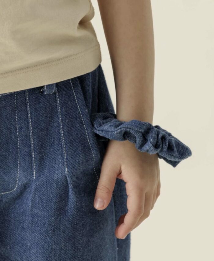 Chouchou volumineux en tissu denim bleu de la marque Apaches Collections. Porté au poignet comme un bracelet.