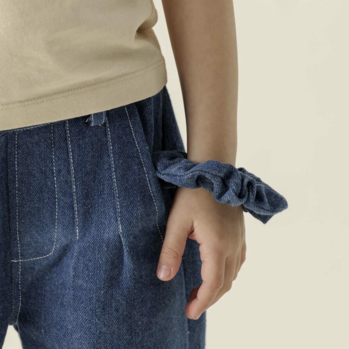 Chouchou volumineux en tissu denim bleu de la marque Apaches Collections. Porté au poignet comme un bracelet.