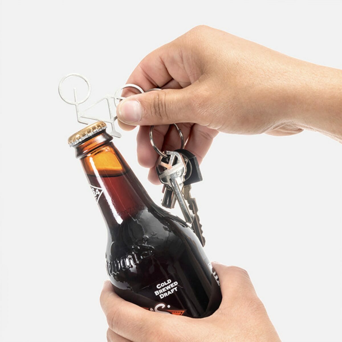 Utilisation du porte-clés décapsuleur en forme de vélo Kikkerland pour ouvrir une bouteille.