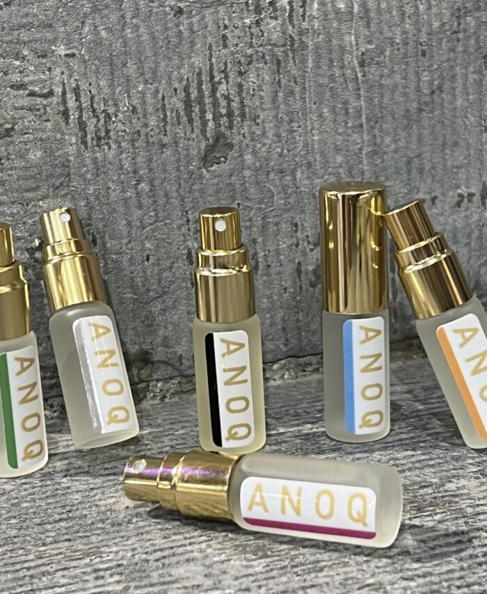Alignement des six flacons de concentrés de parfum d'ambiance Anoq : Accord Audacieux, Ambre Noir, Mandarin des thés, Nature du Lin, Lit de Jasmin, Mystère Boisé.