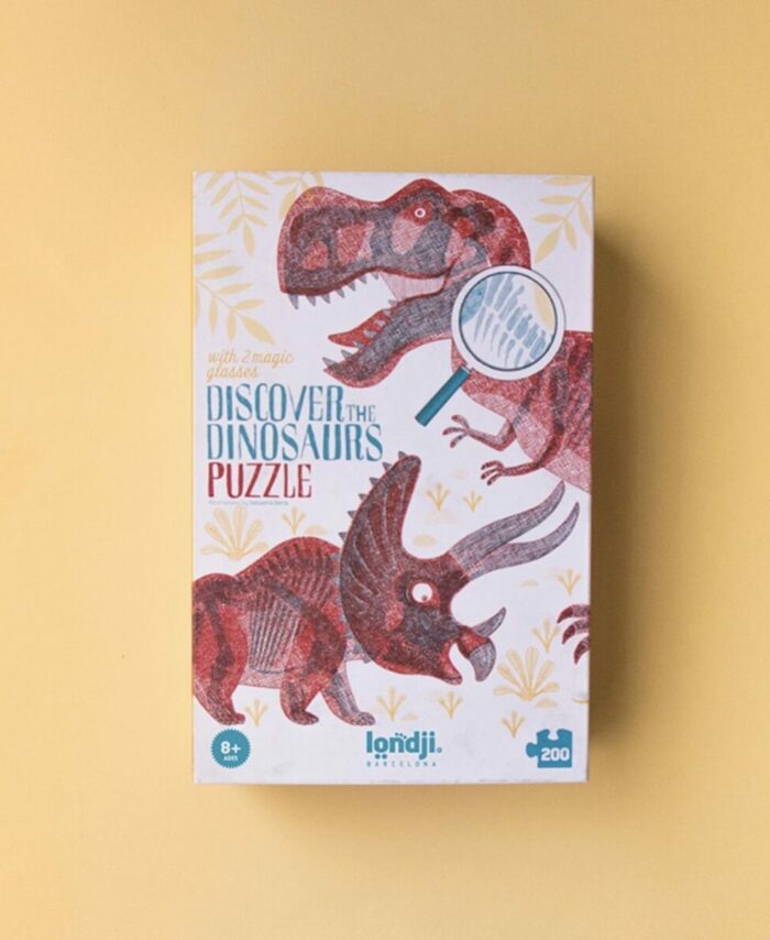 Boîte du puzzle Londji Discover the Dinosaurs montrant un T-Rex rouge et un squelette bleu.