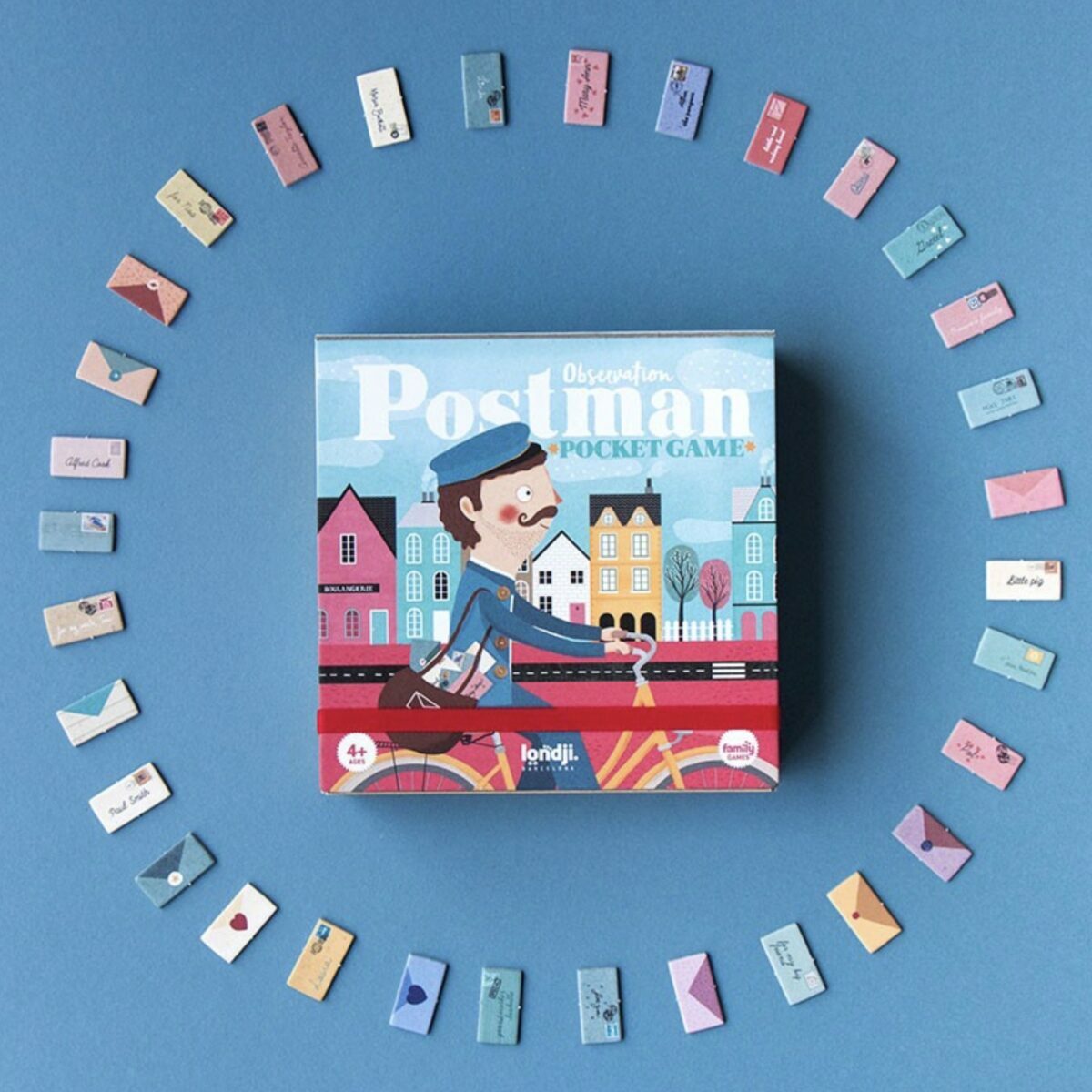 Boîte carrée blanche du jeu Postman Pocket de Londji illustrant un facteur à vélo et des maisons colorées.
